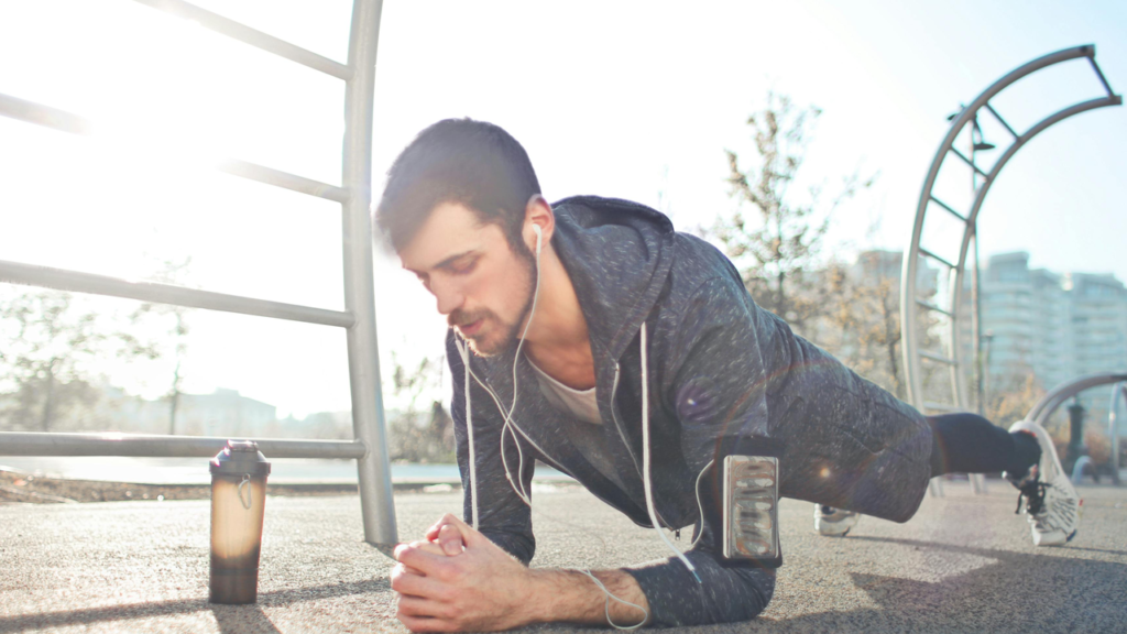 Guy in a plank position, outside, headphones