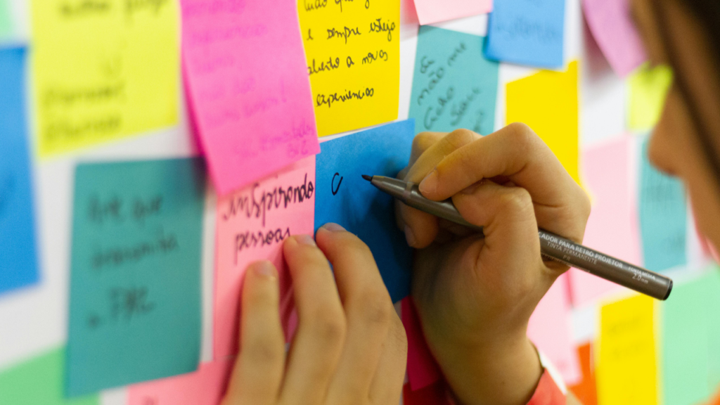 Woman writing goals on a wall of post it notes