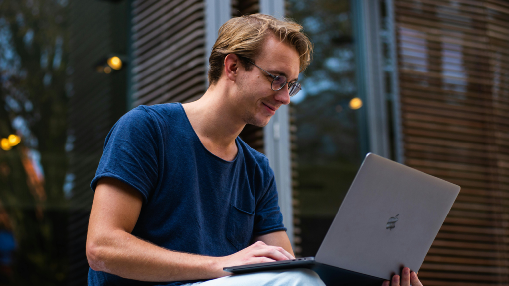 Guy smiling with his laptop outside