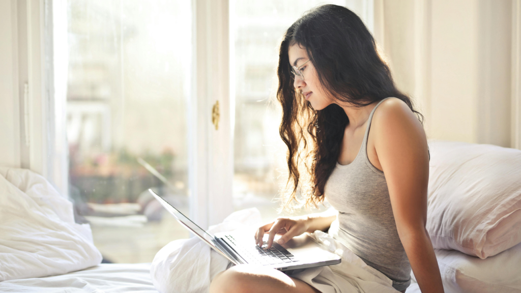 Young woman working on a laptop in bed in the morning