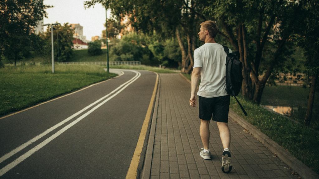 Guy walking on the city sidewalk with backpack.