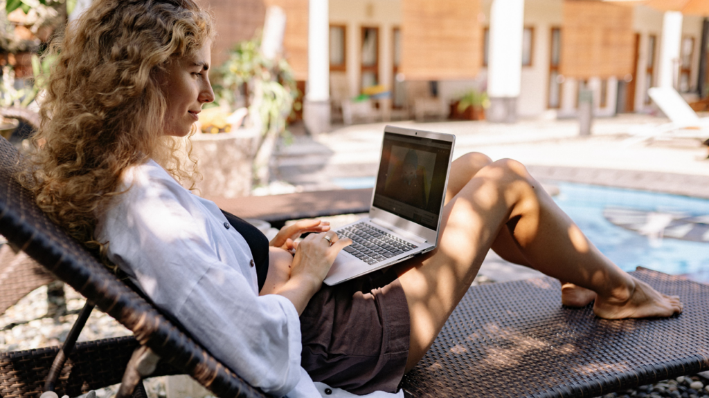 Woman on laptop by the pool